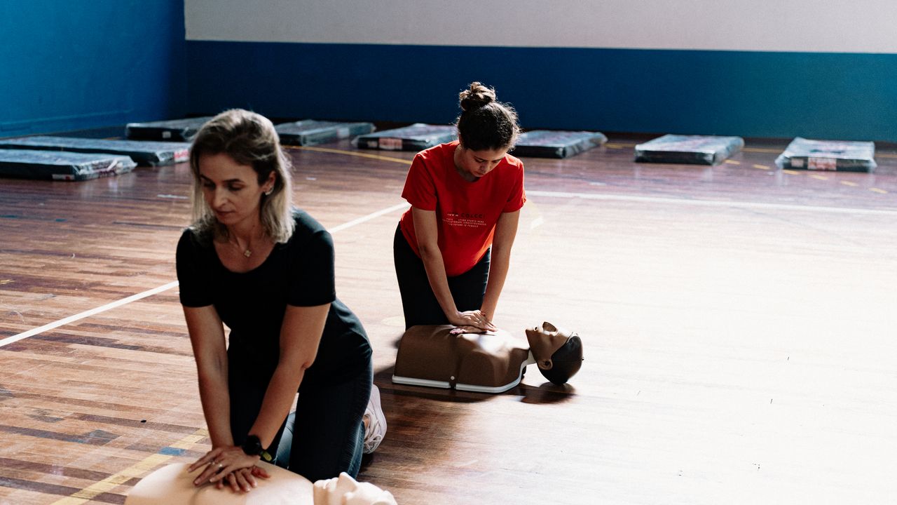 Two people practising CPR on training manikins during a first aid class